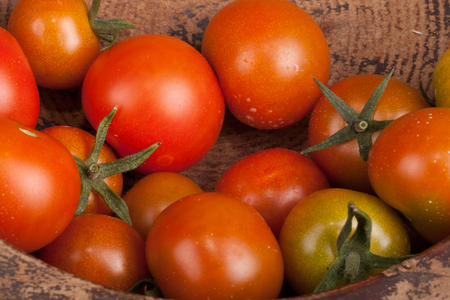 freshly picked tomatoes in old dirty wooden plateの写真素材