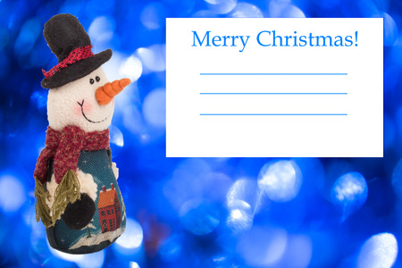 knitted snowman with a card on a background of blue Christmasの写真素材