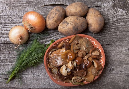 Salty mashrooms, potato, onion, dill and grain in a bowl on a old wooden boardの写真素材