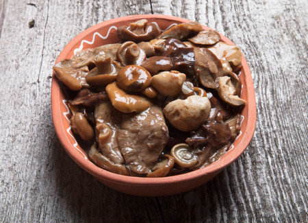 Salty mashrooms in a bowl on a old wooden boardの写真素材