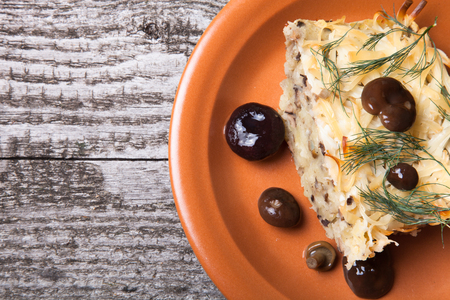 Potato gratin with salty mashrooms and dill in a plate on a old wooden boardの写真素材