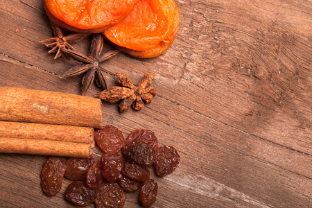 Raisins, cinnamon, anise and dried apricots lying on an old wooden table.の写真素材