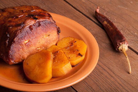 piece of pork, peppers and potatoes in an old wooden tableの写真素材