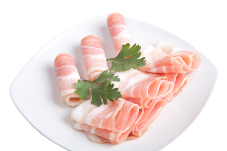 Bacon slices with parsley on a plate isolated on white backgroundの写真素材