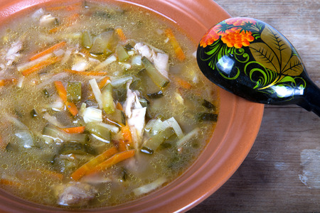 Soup in a plate with a wooden spoon on a boardの写真素材
