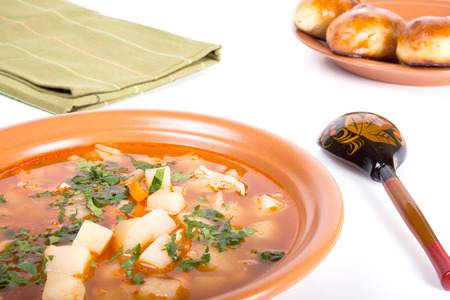 plate of vegetable soup, a wooden spoon and cakes on a light backgroundの写真素材