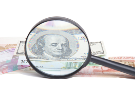 banknotes of different countries under a magnifying glass isolated on white background.Portrait Of Benjamin Franklinの写真素材
