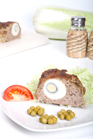 meatloaf with egg tomato and green peas on a white backgroundの写真素材