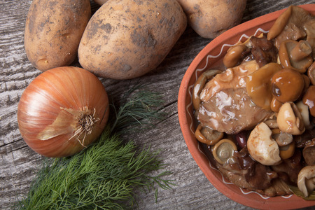 Salty mashrooms, potato, onion, dill and grain in a bowl on a old wooden boardの写真素材