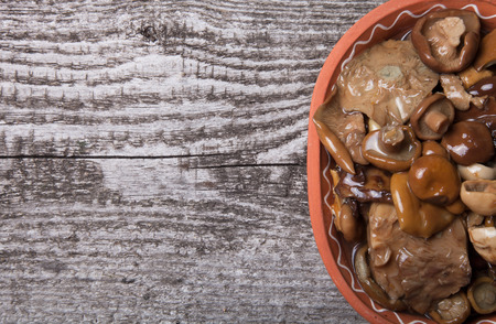 Salty mashrooms in a bowl on a old wooden boardの写真素材