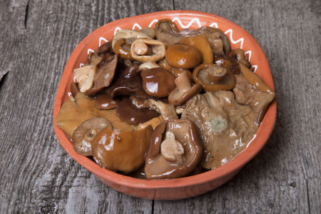 Salty mashrooms in a bowl on a old wooden boardの写真素材