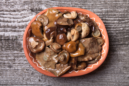 Salty mashrooms in a bowl on a old wooden boardの写真素材