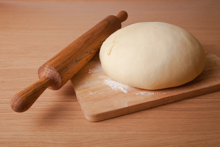 dough on a board and rolling pin with flour for sprinklingの写真素材