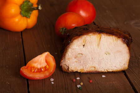 piece of pork, peppers and tomatoes on an old wooden tableの写真素材