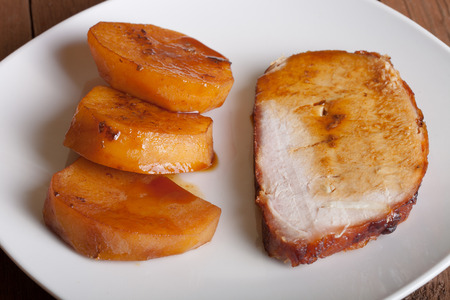 piece of pork with potatoes on a white plateの写真素材