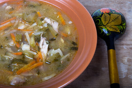 Soup in a plate with a wooden spoon on a boardの写真素材