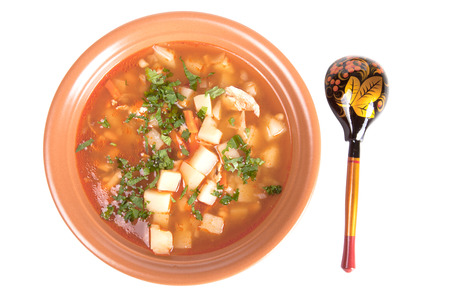 plate of vegetable soup and a wooden spoon isolated on white backgroundの写真素材