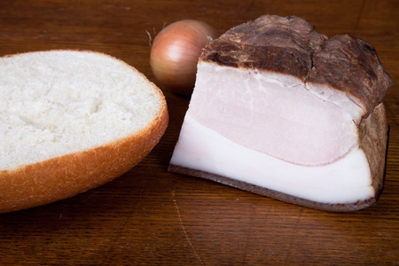 Ukrainian smoked lard and a piece of bread and onions on the old board. Shallow depth of fieldの写真素材