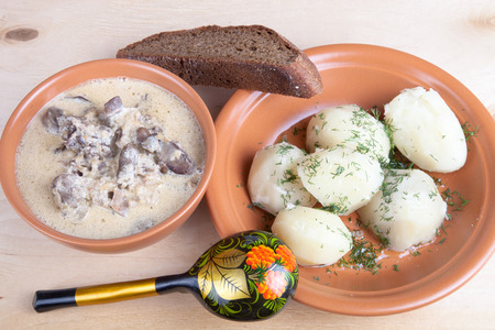 Soup of chiken liver and boiled potato with dill on a wooden boardの写真素材