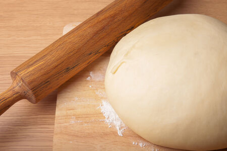 dough on a board and rolling pin with flour for sprinklingの写真素材