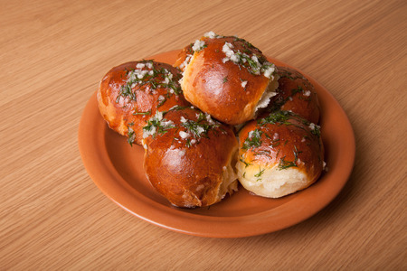 freshly baked rolls lying in the ceramic dish on wooden tableの写真素材