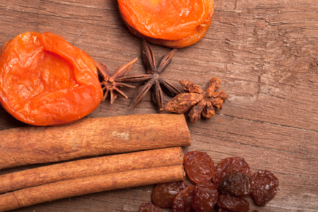 Raisins, cinnamon, anise and dried apricots lying on an old wooden table.の写真素材