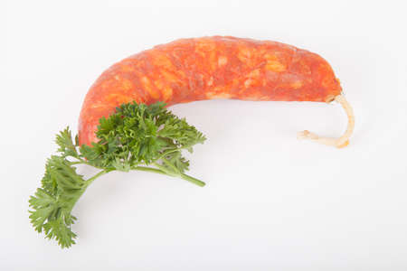 fresh chorizo sausage and a sprig of parsley on a white backgroundの写真素材