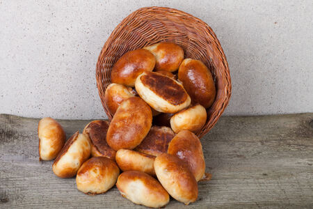 pies with meat or cabbage in a wicker basket on a wooden background.の写真素材