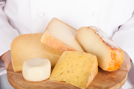 different varieties of cheese on a board in the hands from the cook