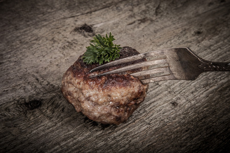 cutlet and slice on a fork on old wooden table.Tintedの写真素材