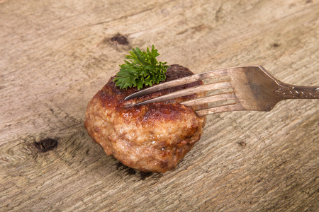 cutlet and slice on a fork on old wooden tableの写真素材