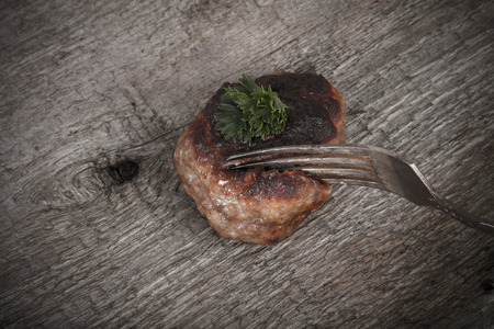 cutlet and slice on a fork on old wooden tableの写真素材