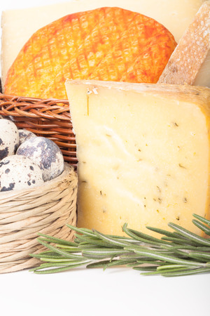 several varieties of cheese in a wicker basket and basket quail eggsの写真素材