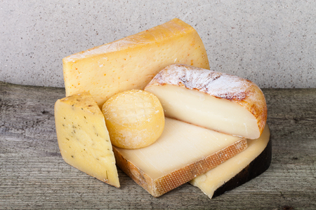 Head and various pieces of cheese on a wooden tableの写真素材
