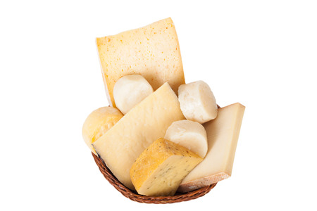 Different cheeses and a bunch of parsley lying in a wicker basket isolated on white backgroundの写真素材