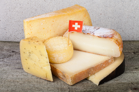 Head and various pieces of cheese on a wooden tableの写真素材