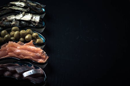 Fish assortment and olives on a plate on a dark background. With space for text. tintedの写真素材