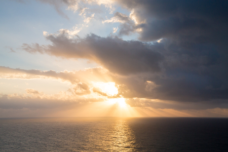 Dramatic sunset rays through a cloudy dark sky over the ocean. Tintedの写真素材