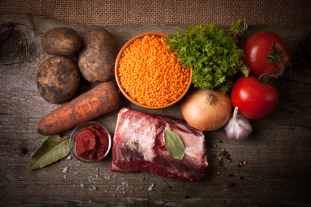 Ingredients for Turkey vegetable soup with red lentils, lying on an old wooden board and sacking.の写真素材