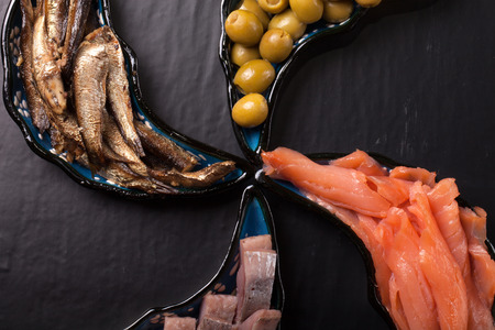 Fish assortment and olives on magic plates on a dark backgroundの写真素材