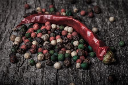 red hot chili peppers and peppercorns on an old wooden tableの写真素材