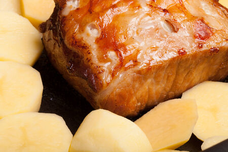 piece of pork, peppers and potatoes in an old wooden tableの写真素材