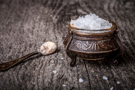 sea salt in an old utensils and a small spoon on a wooden tableの写真素材