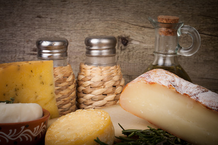 different cheese, olive oil, rosemary, salt and pepper on a wooden backgroundの写真素材