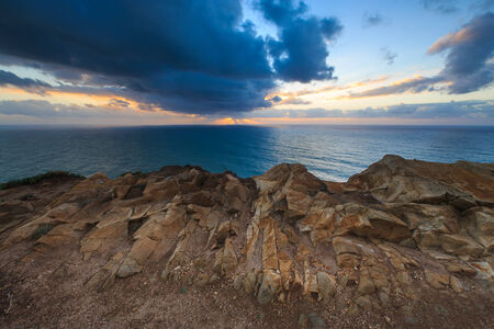 Dramatic sunset rays through a cloudy dark sky over the oceanの写真素材