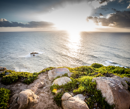 Dramatic sunset rays through a cloudy dark sky over the oceanの写真素材