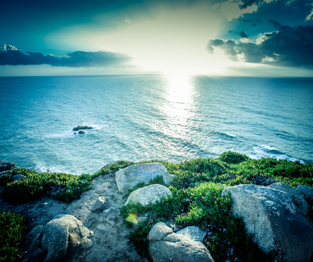 Dramatic sunset rays through a cloudy dark sky over the oceanの写真素材