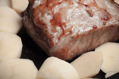 piece of pork, peppers and potatoes in an old wooden tableの写真素材