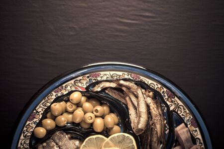 Assorted fish on a plate on a dark background. With space for text. tinted