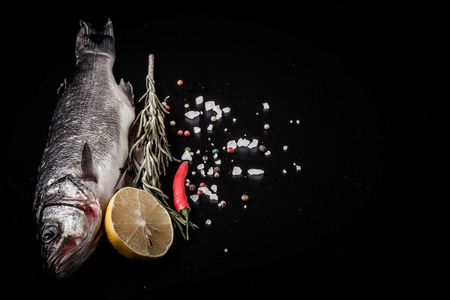 Fresh sea fish lying on dark background with spices. Space for textの写真素材